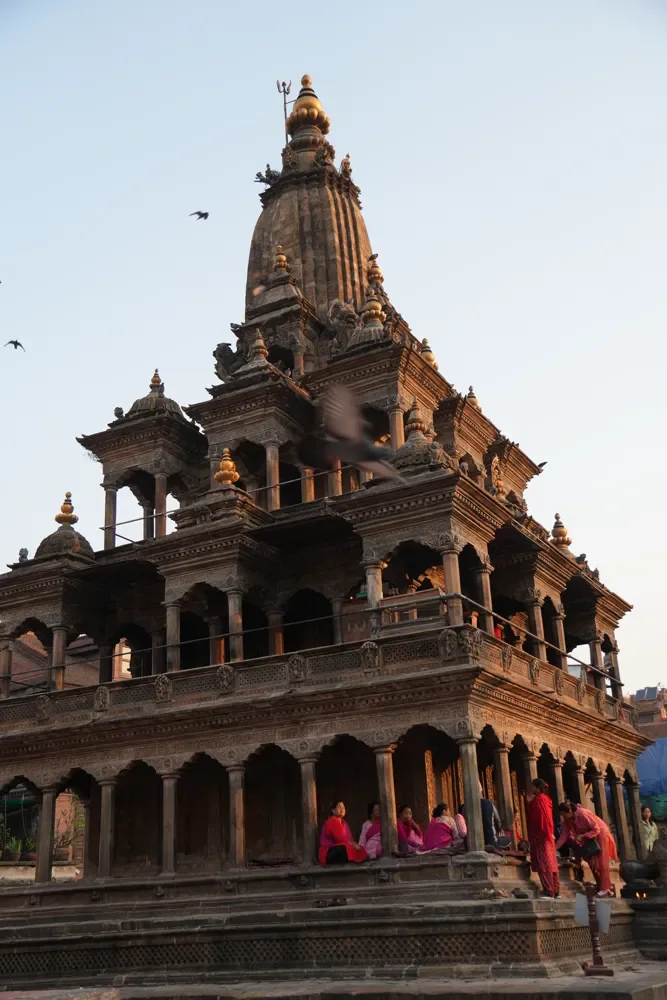 Krishna Mandir in Patan, a stone temple with a tall spire and carved arches, lit by soft evening light